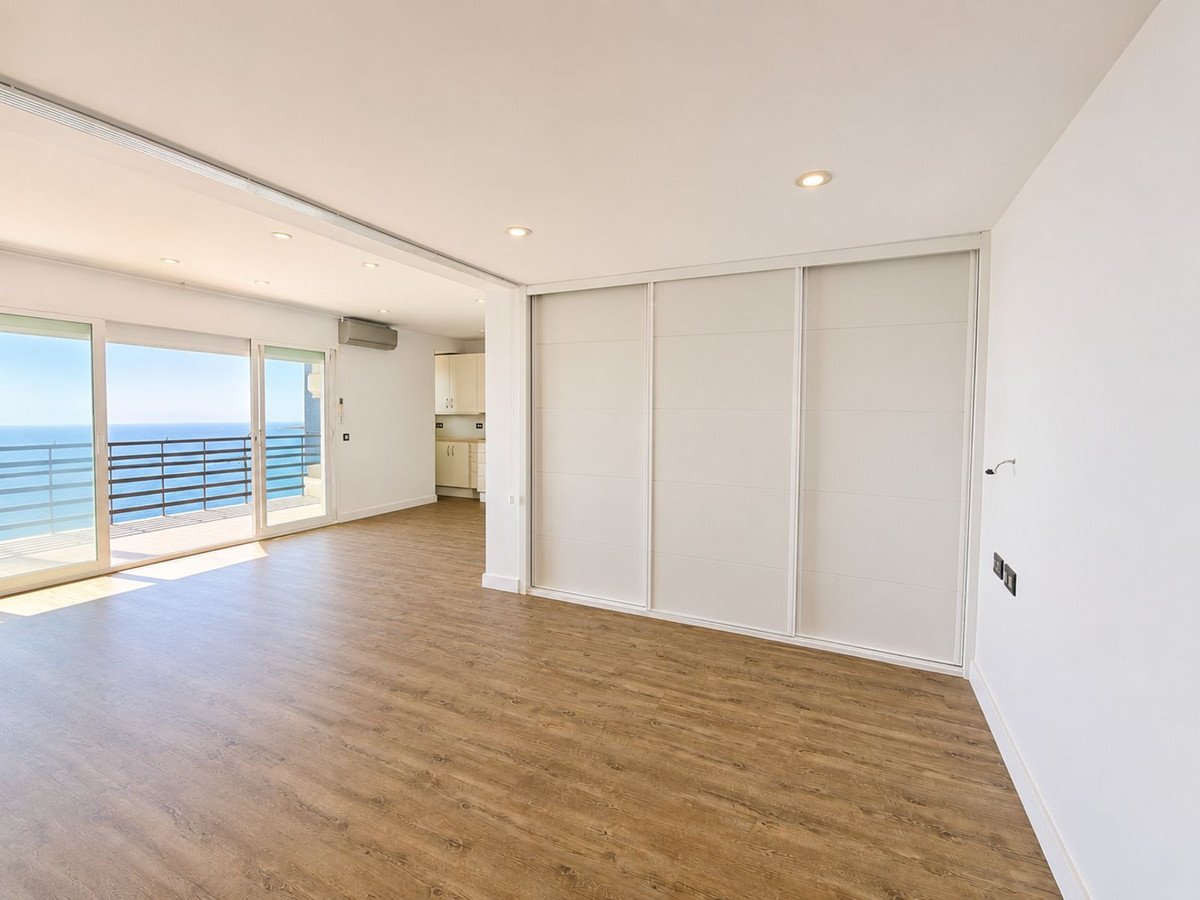 Spacious living area with large sliding doors leading to a balcony with an ocean view and built-in wardrobes.
