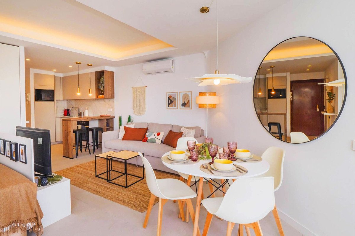 Modern studio apartment with open-plan living, dining, and kitchen area, featuring a sofa, dining table, and breakfast bar.