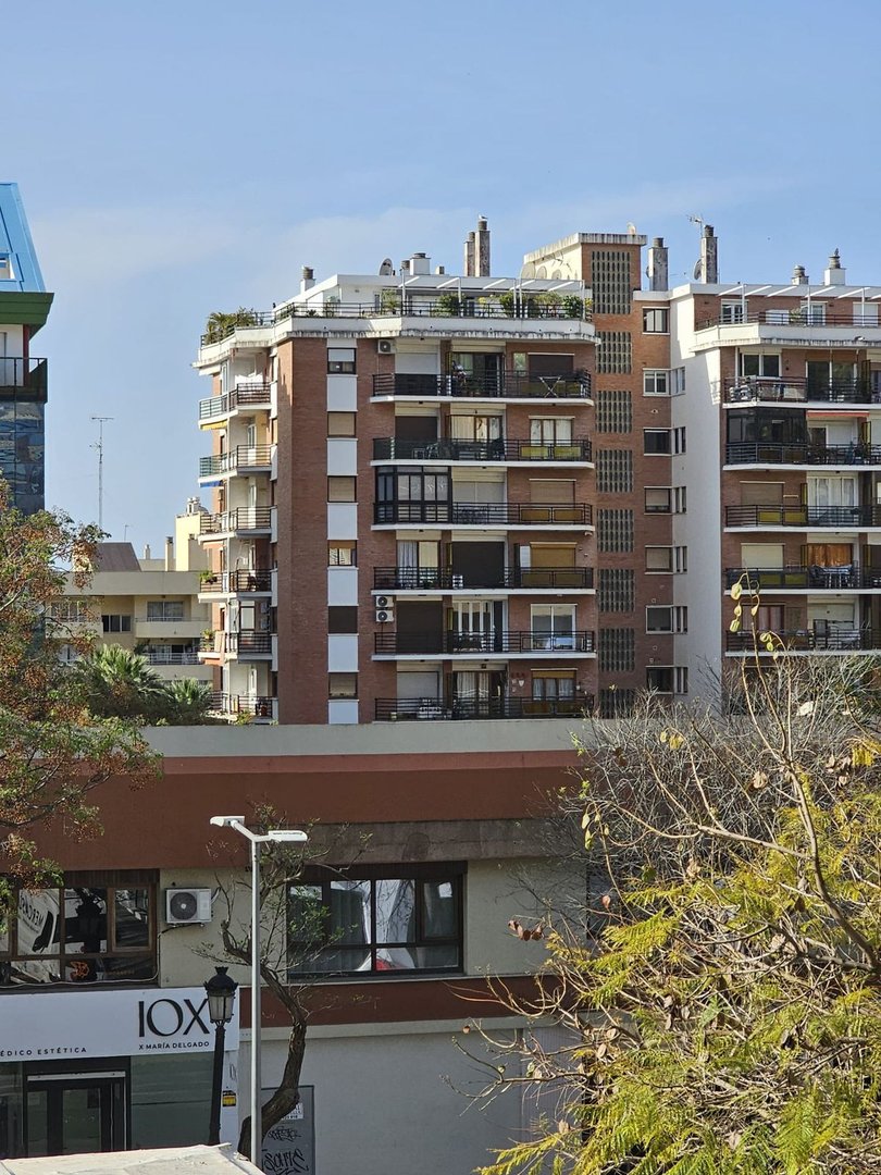 Apartment buildings with multiple balconies and windows under a clear blue sky.