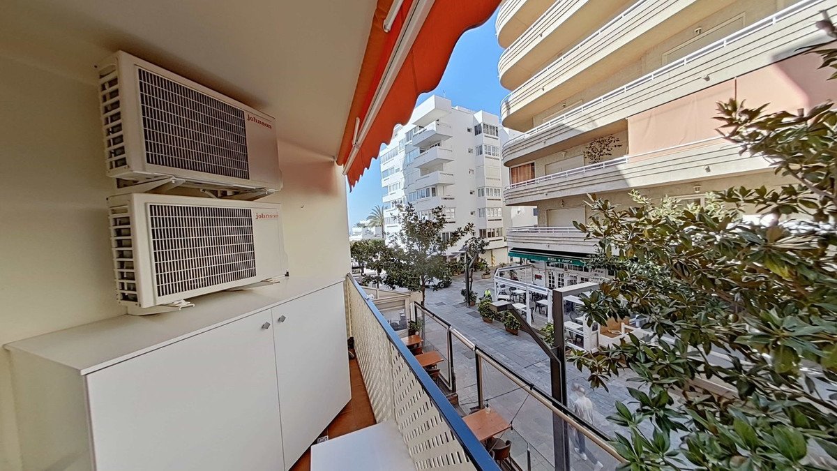 Balcony with air conditioners overlooking a city street with buildings and trees