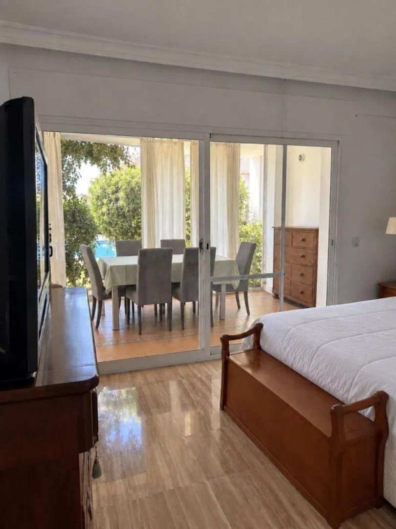 Bedroom with a view to a dining area and a pool outside through sliding glass doors.