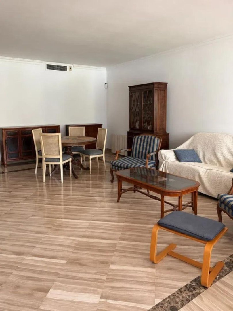 Living and dining area with a round table, chairs, sofa, coffee table, and wooden cabinets.