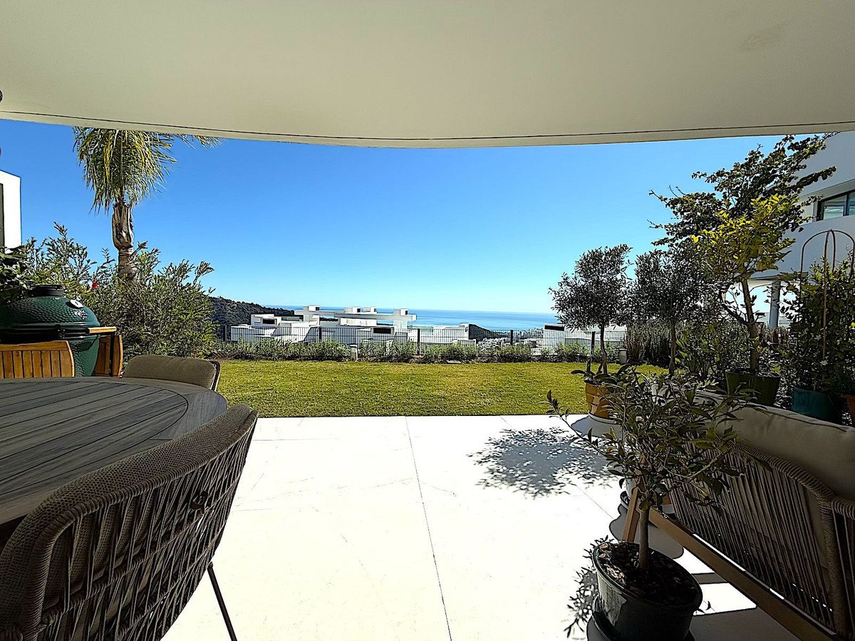 Patio with outdoor furniture overlooking the sea and distant buildings