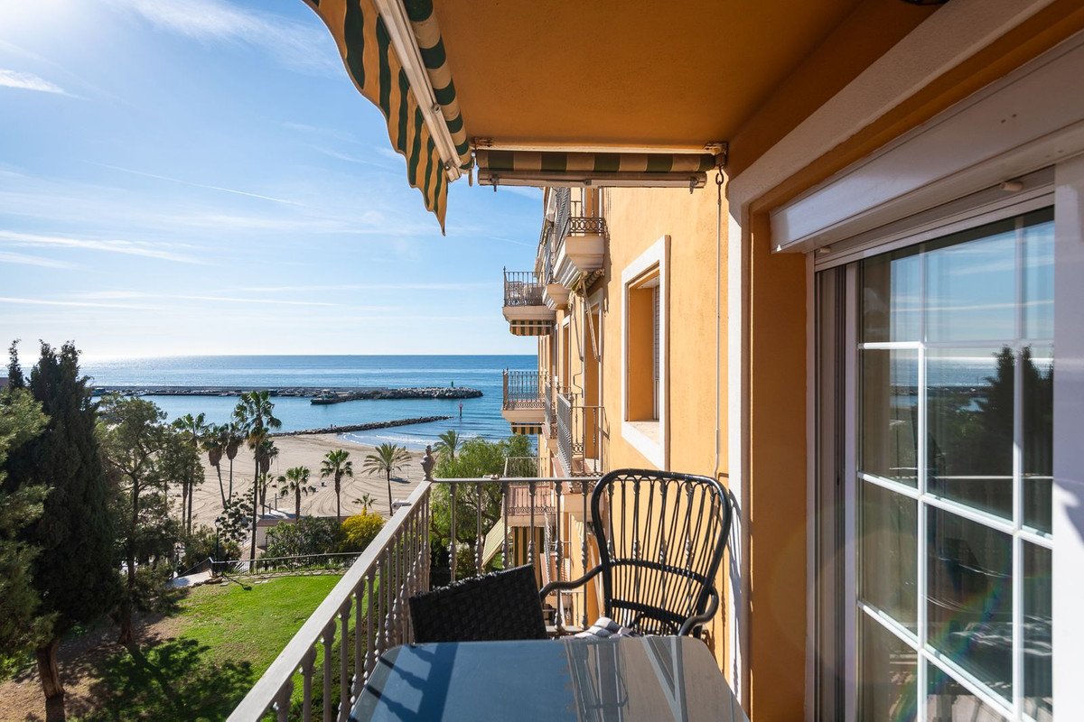 Balcony with ocean view, palm trees, and beach from a hotel room.