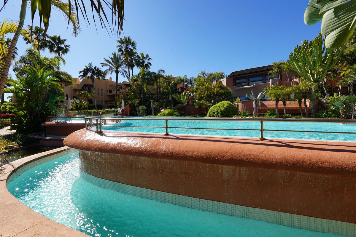 Luxurious swimming pool surrounded by tropical palm trees and resort buildings