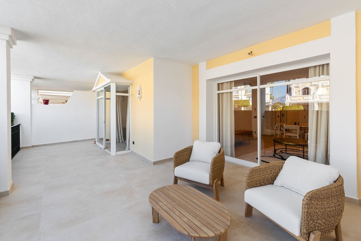 Spacious outdoor terrace with woven chairs, a coffee table, and sliding glass doors leading inside.