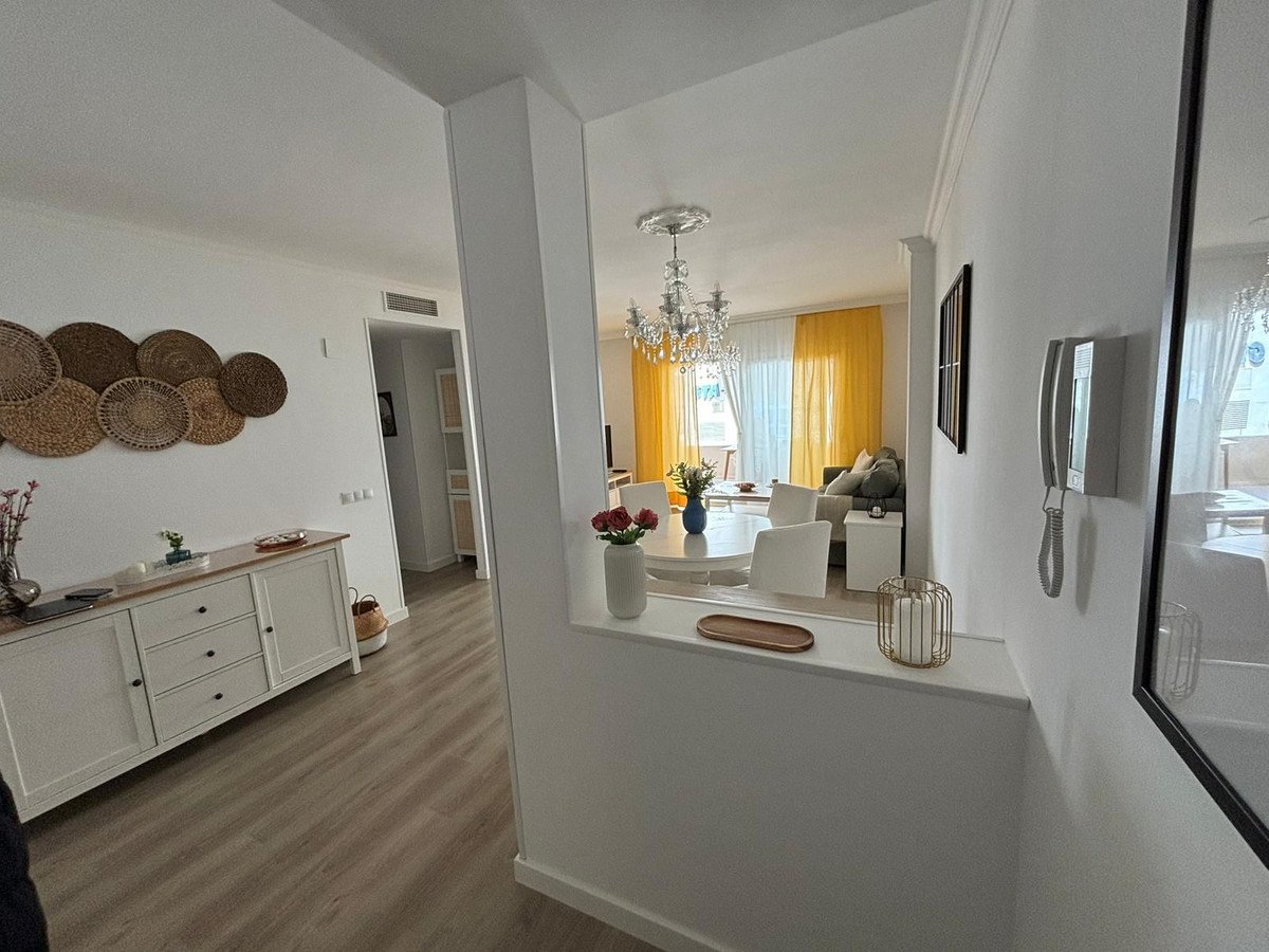 Elegant living and dining area with a crystal chandelier, white furniture, and bright yellow curtains.