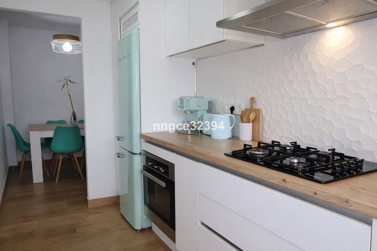 Modern kitchen featuring a teal refrigerator, gas stove, and hexagonal wall design