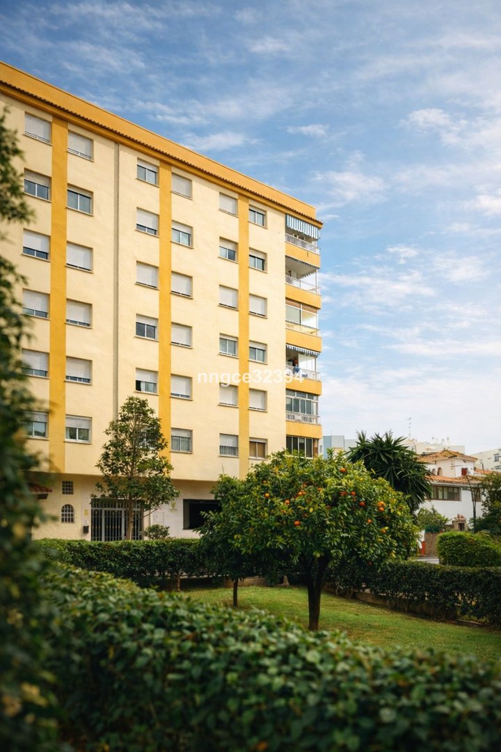 Yellow apartment building with balconies and lush garden