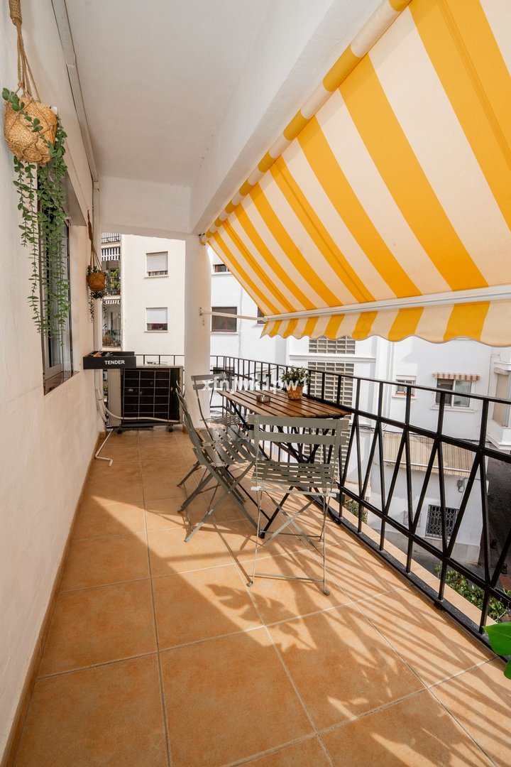 Yellow-striped awning covering a terrace with a dining table and chairs