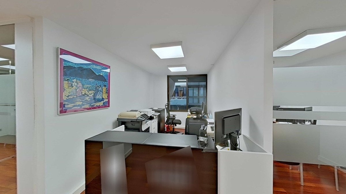 Office reception area with a dark wood desk, computers, printer, and artwork on the wall.