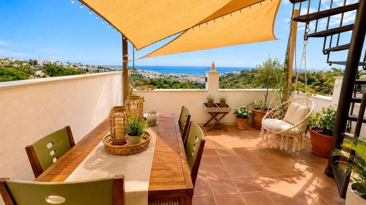 Outdoor dining terrace with sea views, comfortable seating, and decorative plants under a sunshade.
