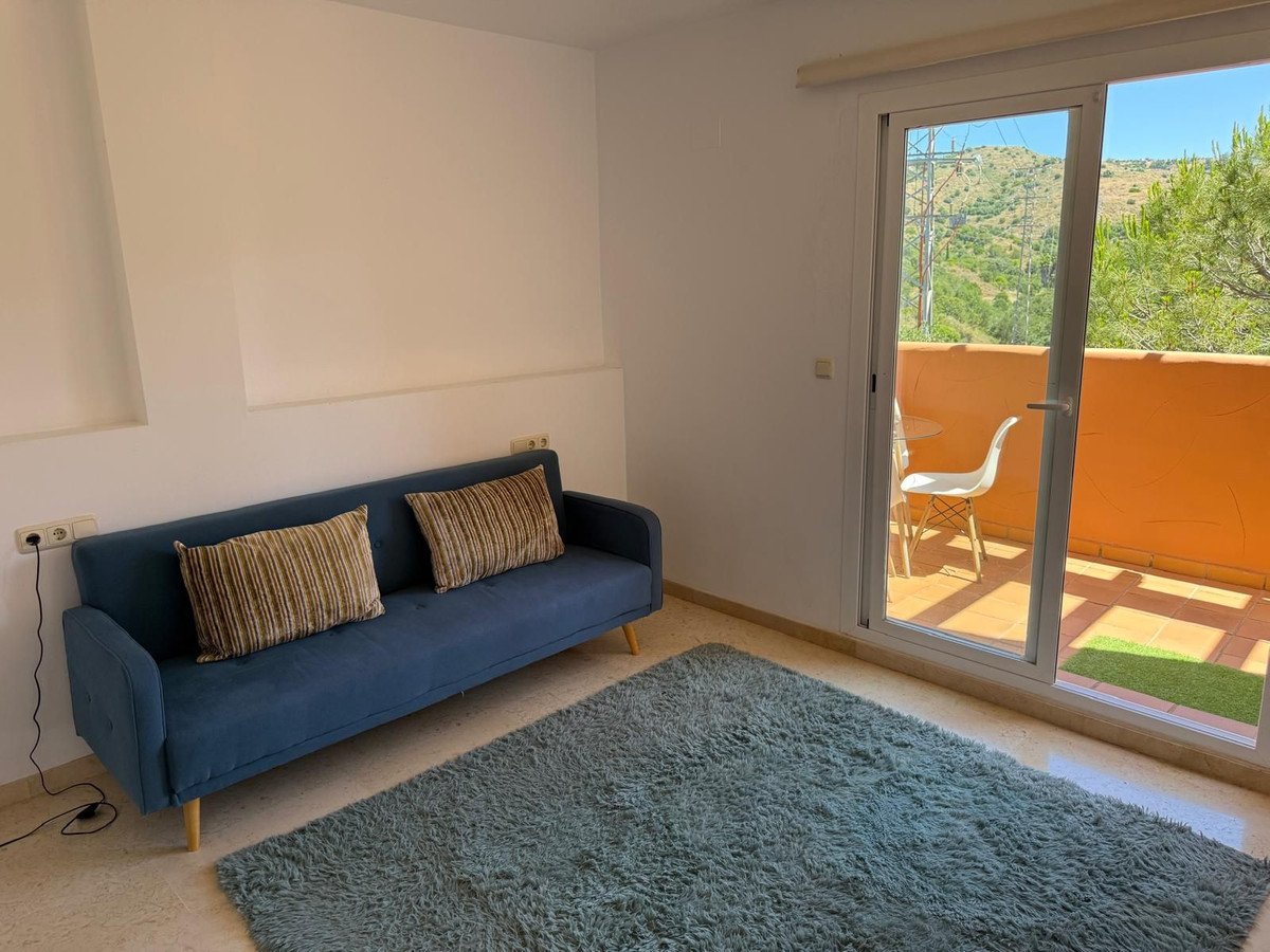 Living room with blue sofa, rug, and sliding glass door leading to a balcony with mountain views.
