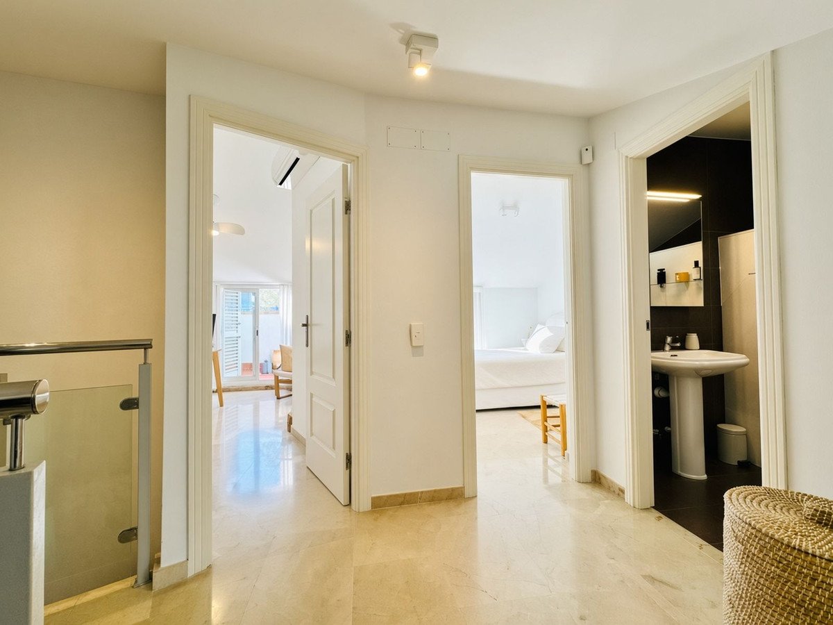 Hallway view showing doors to a bedroom, a bathroom, and a balcony with natural light and modern finishes.