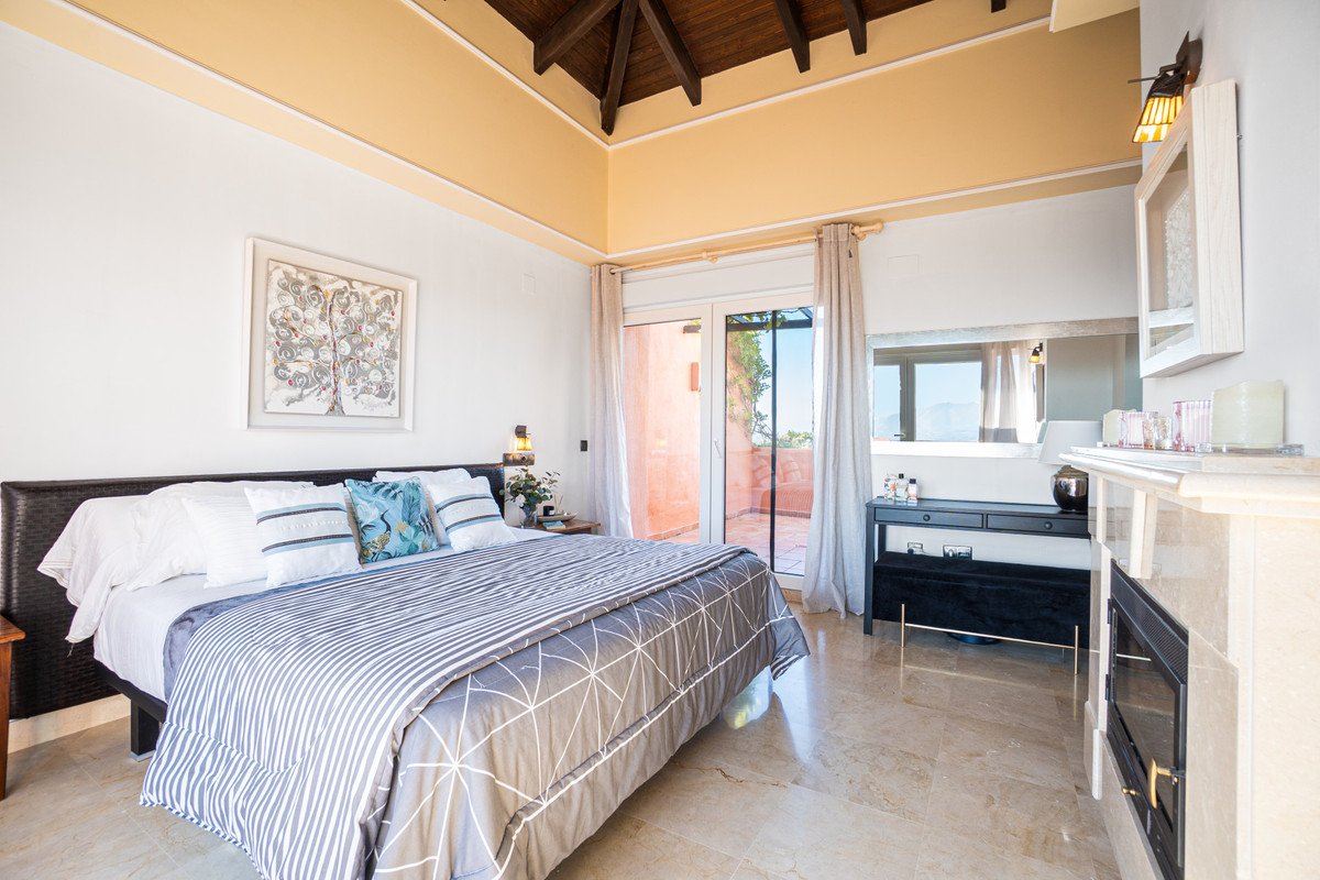 Spacious bedroom with vaulted ceiling, fireplace, and balcony view.