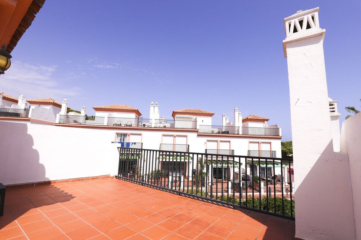 White apartment complex with red tile rooftops and clear blue sky view