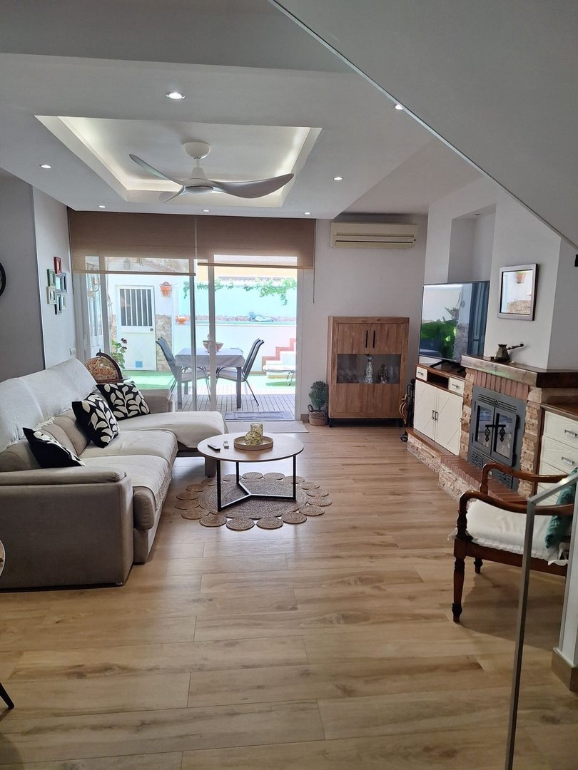 Spacious living room with a sectional sofa, coffee table, fireplace, and view of the terrace and pool area outside.