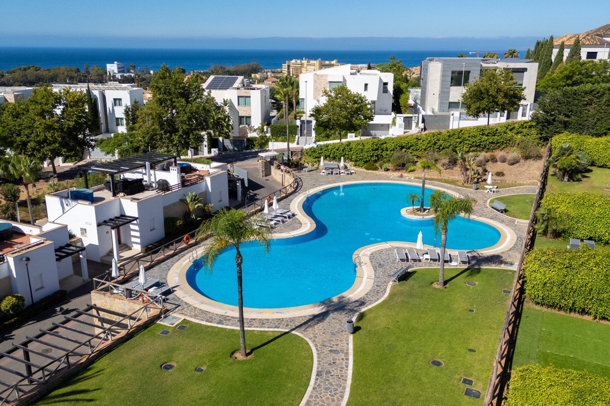 Aerial view of a luxury villa with a large pool, lush greenery, and ocean views.