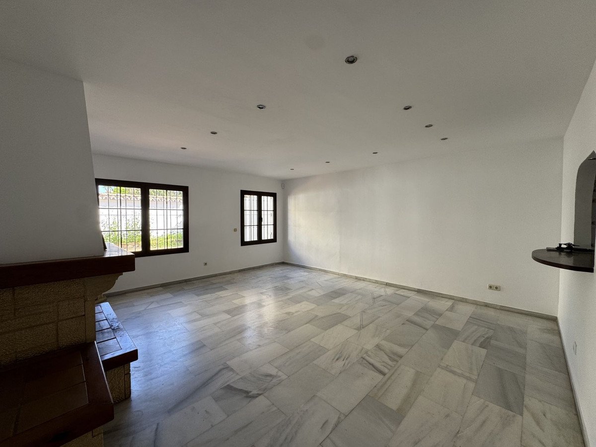 Empty living room with marble flooring and large windows overlooking greenery