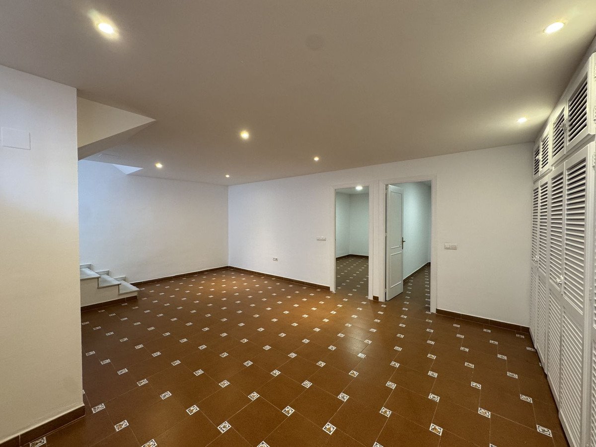 Empty living room with brown tiled floor and white walls
