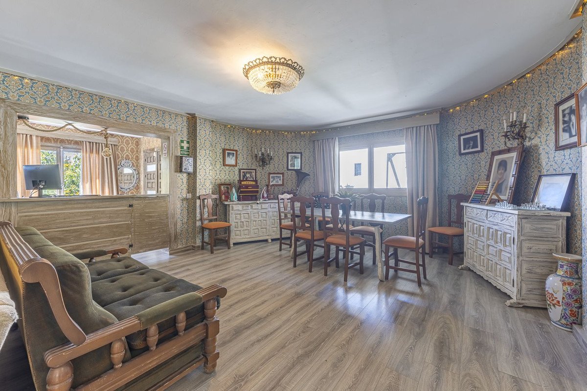 Living and dining room with a green sofa, bar area, and a dining table set for meals.