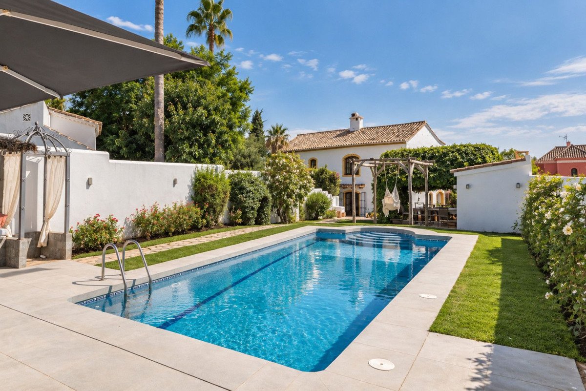 Luxury villa with a swimming pool and garden, featuring a hammock swing and outdoor seating area under a pergola.