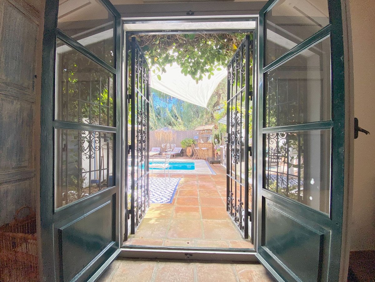 Open double doors leading to a garden with a swimming pool and outdoor seating