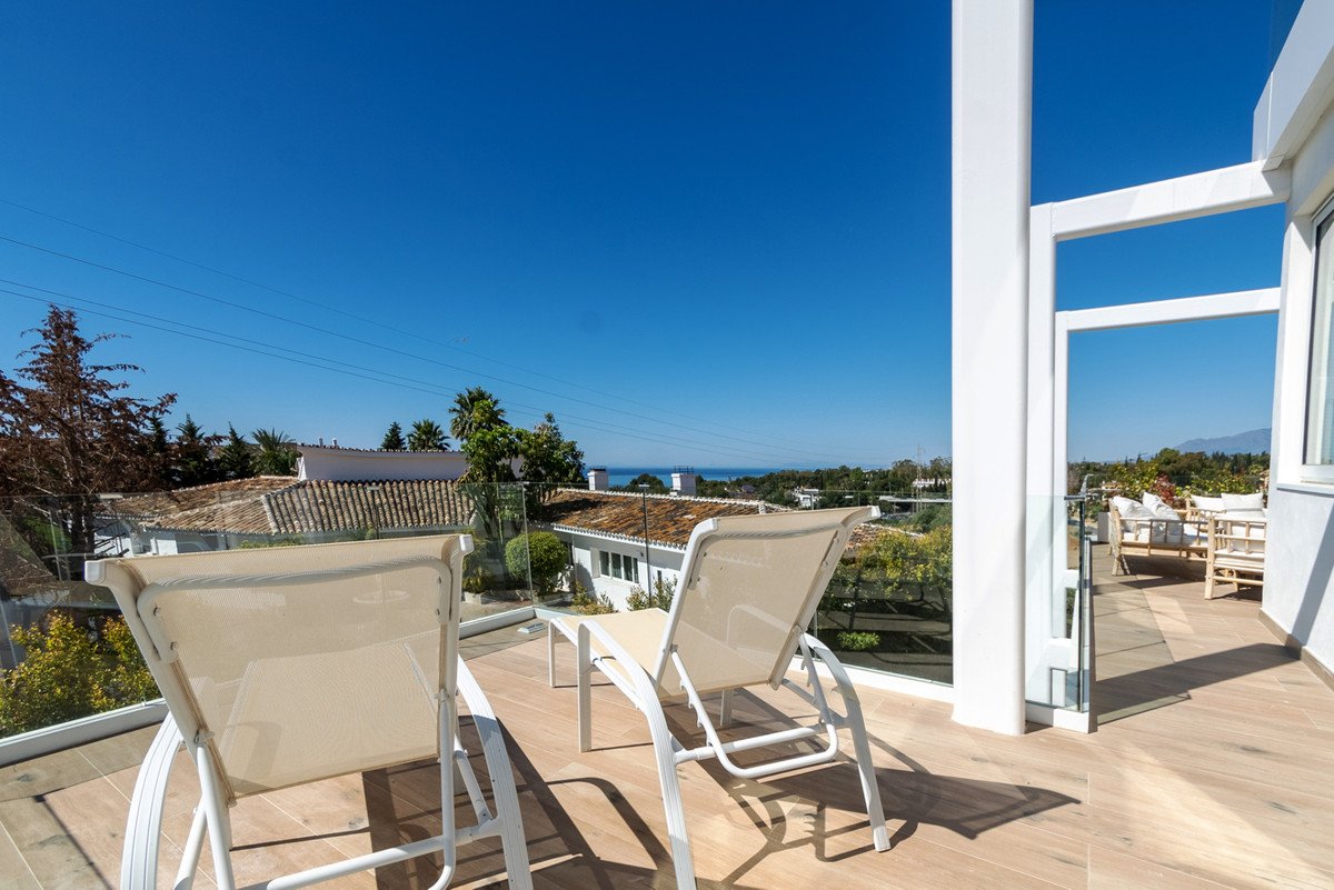 Balcony with two lounge chairs overlooking the sea and clear blue sky