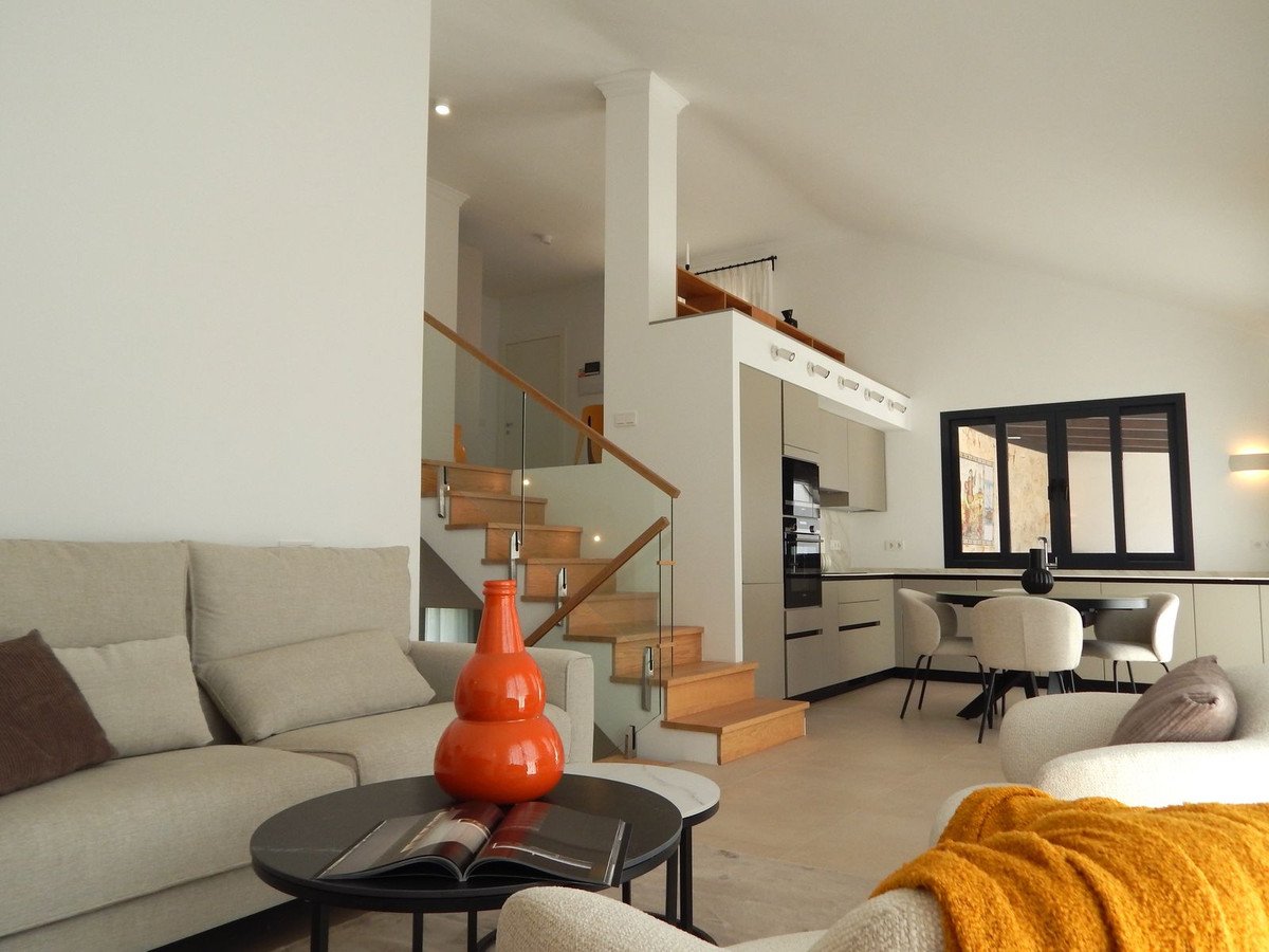 Modern living room with open kitchen, staircase, and dining area.