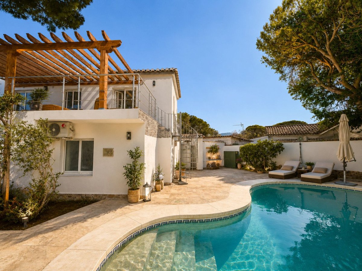 A villa with a swimming pool, sun loungers, and a covered pergola terrace on a sunny day.