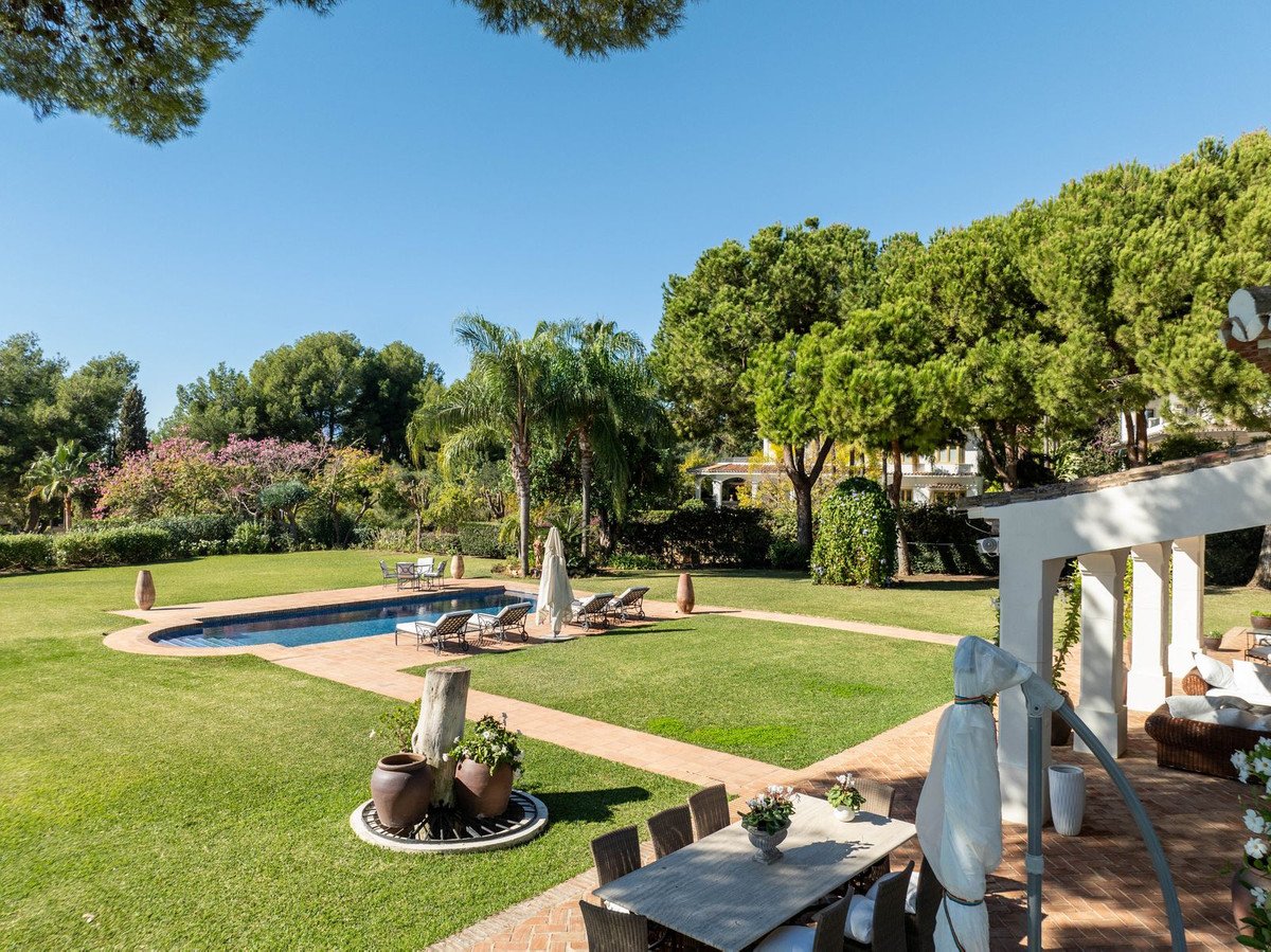 Luxurious garden with swimming pool, lounge chairs, and outdoor dining area