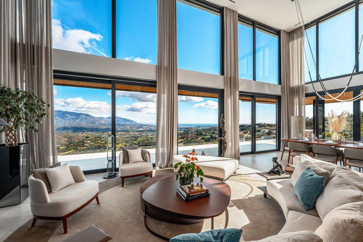 Sunlit living room with large windows overlooking a scenic mountain landscape