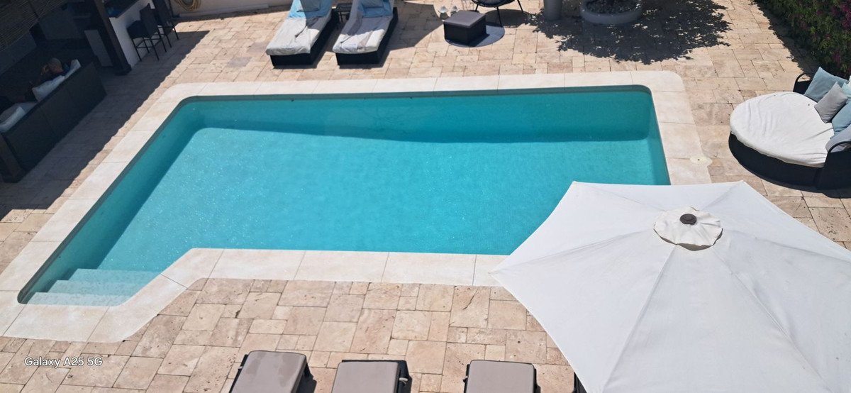 Swimming pool with lounge chairs and a large umbrella on a sunny patio