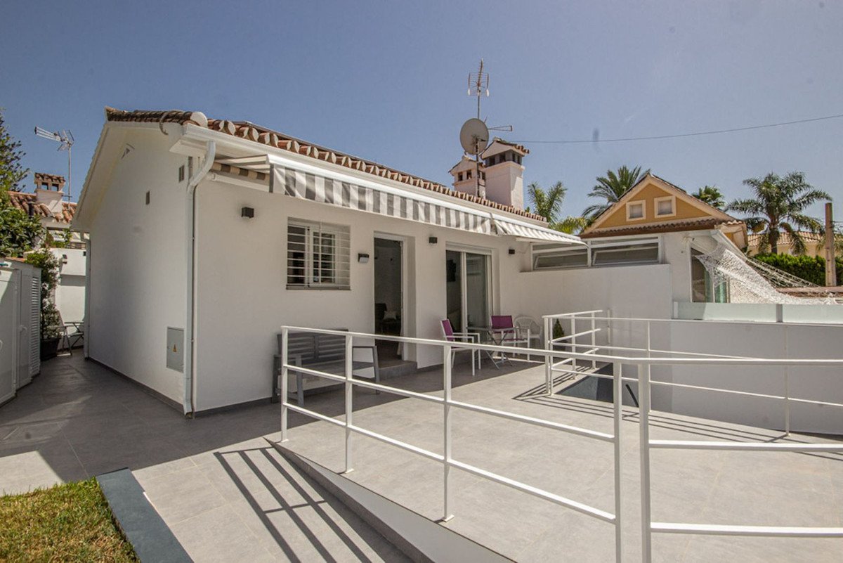 Spacious outdoor terrace with white railings, seating area, and striped awning. Sunny day with blue sky.