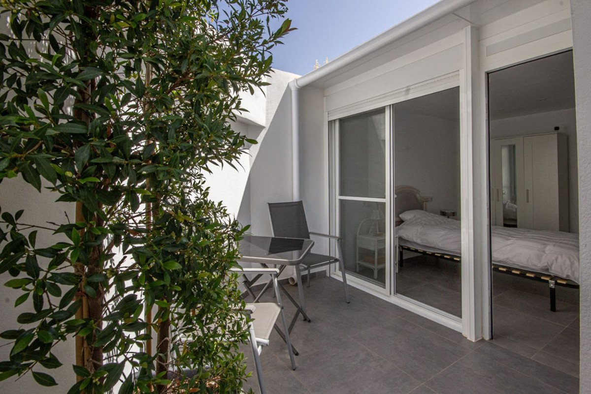 View of a bedroom from a balcony with a table and chairs, featuring a large wardrobe and a bed.