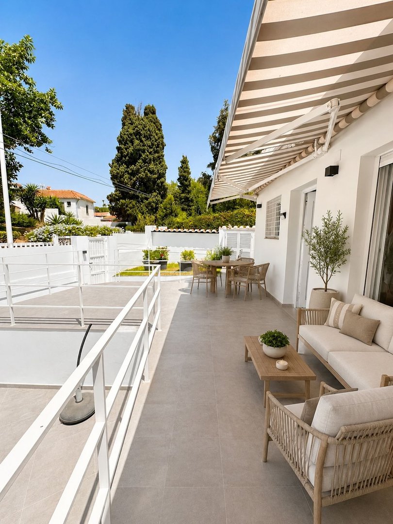 Outdoor patio with lounge seating, dining area, and striped awning under clear blue sky