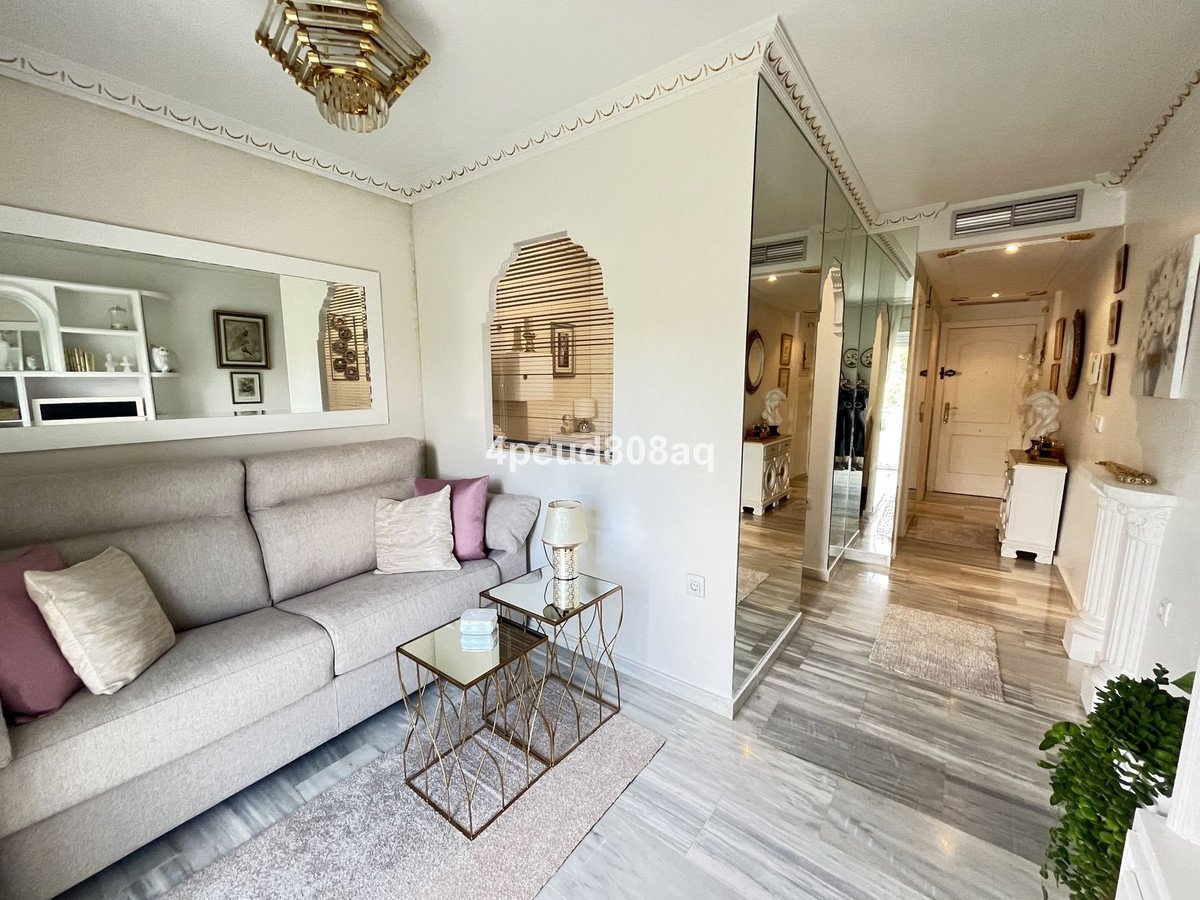 A modern living room with a sofa, mirrored closets, and a hallway leading to a door.