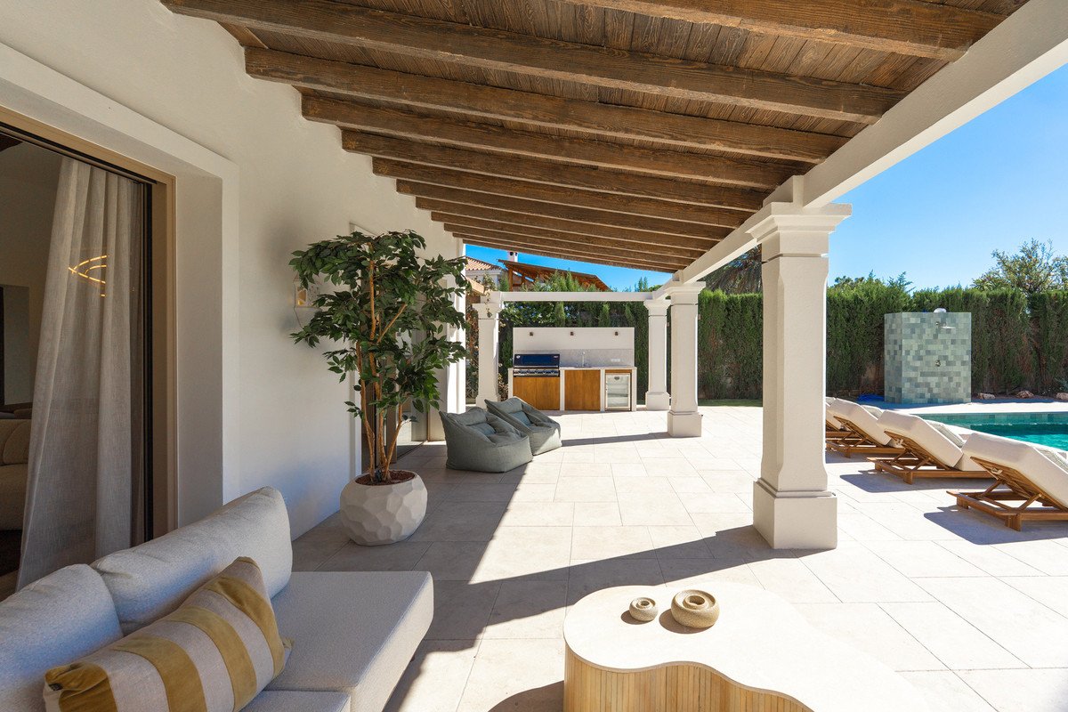 Outdoor patio with lounge seating, pool, and covered wooden beams.