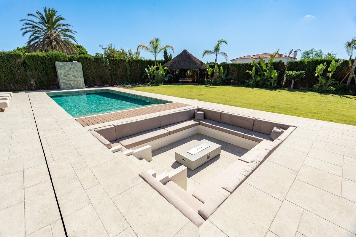 Outdoor lounge area with sunken seating, pool, and garden view