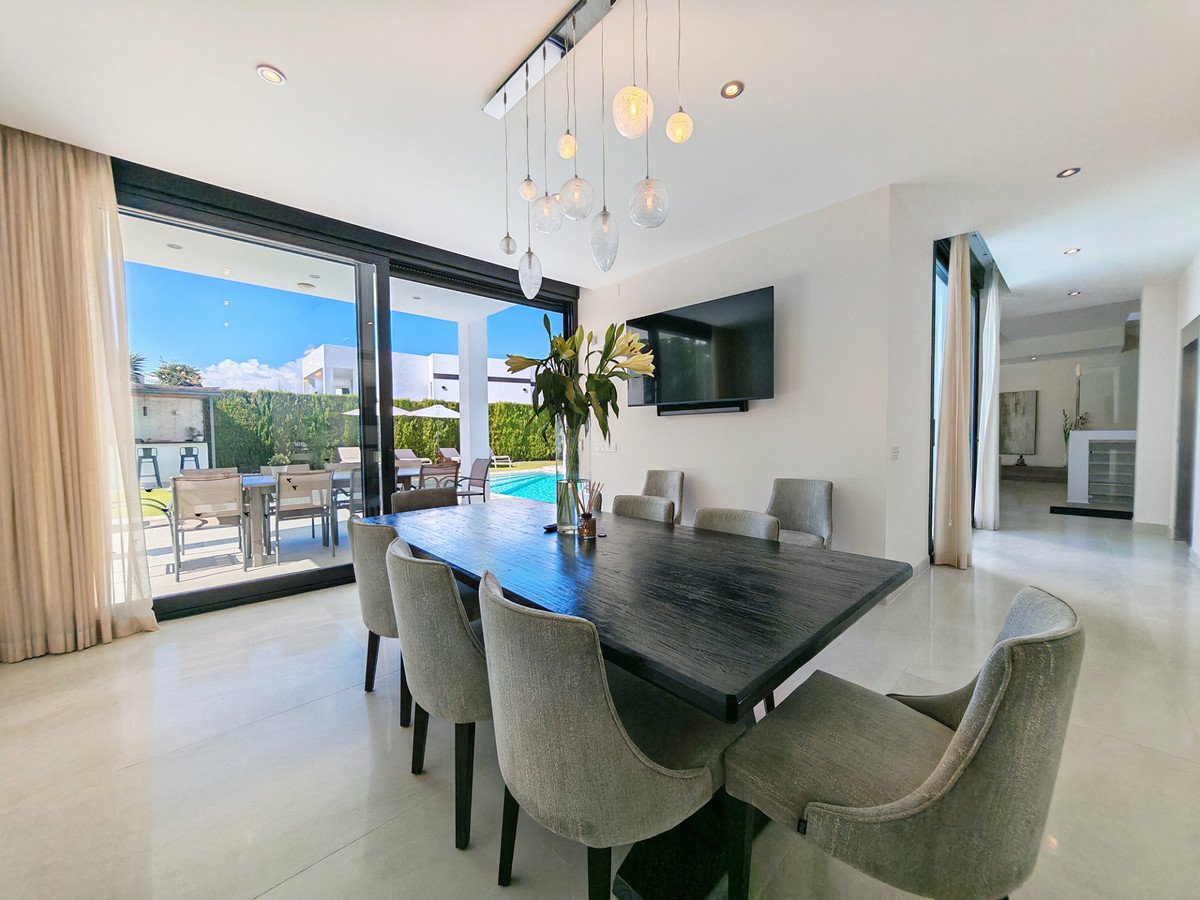 Modern dining room with large table, chairs, and sliding glass doors to pool view