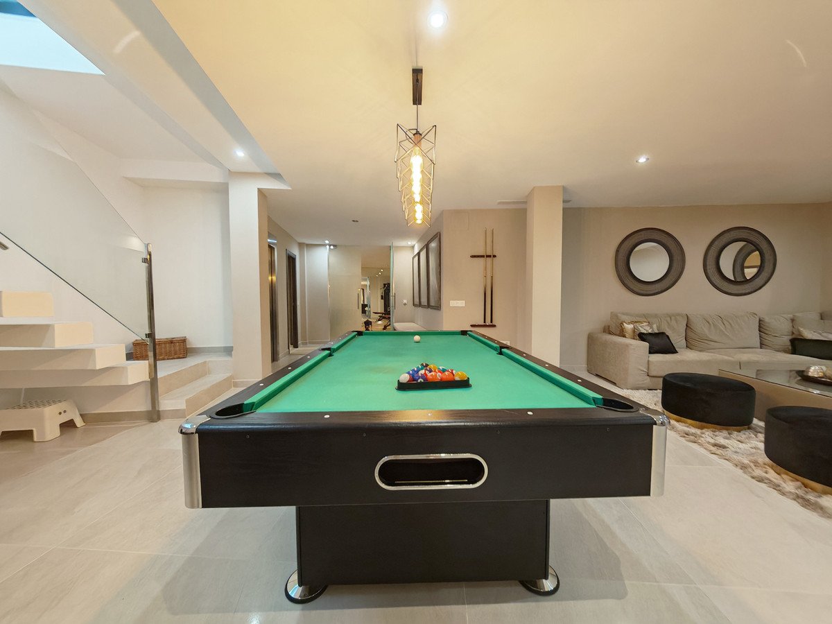 Modern game room with pool table, living area, and staircase visible.