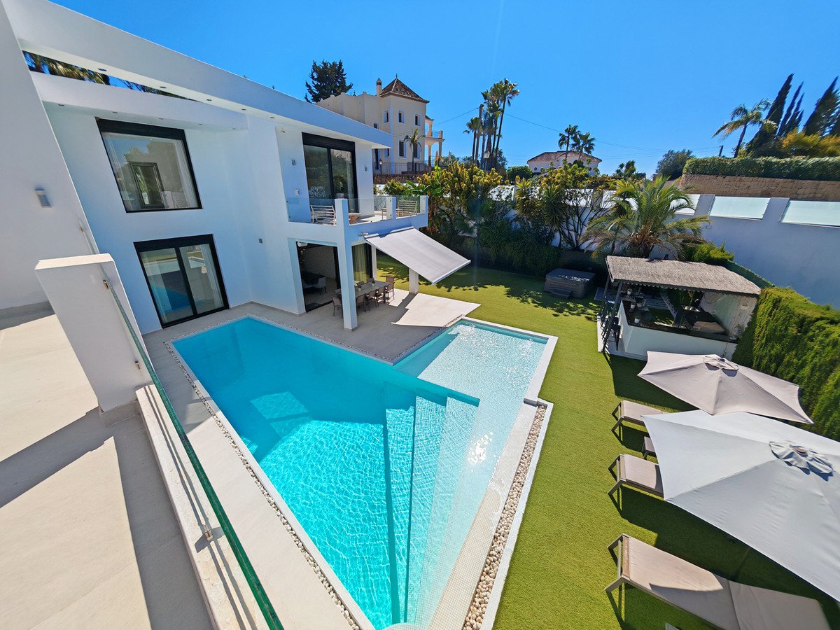 Modern villa with swimming pool, outdoor seating, and sunny garden view