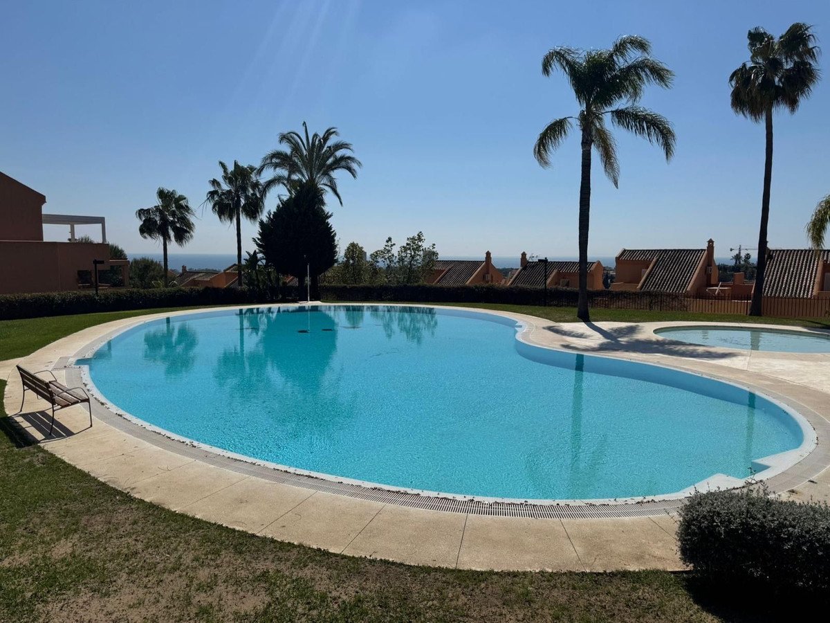 A resort swimming pool with palm trees and a clear blue sky.