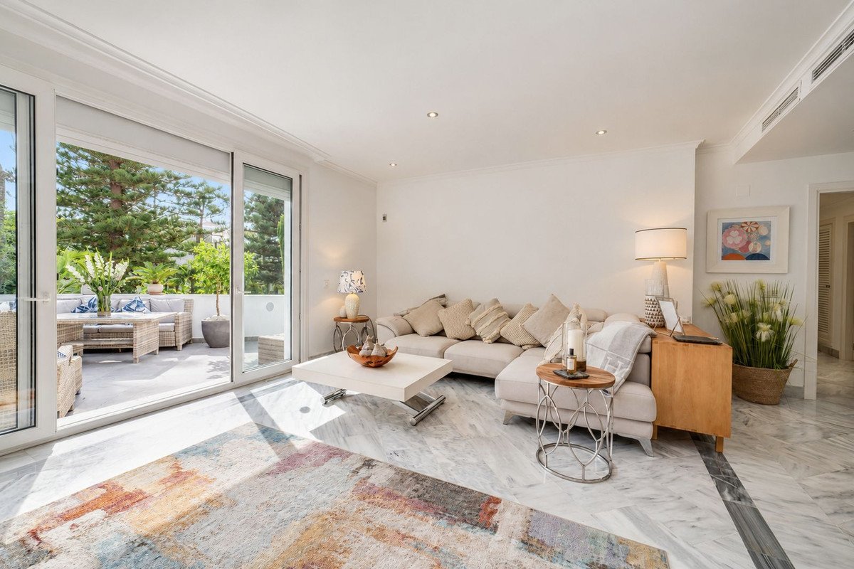 Modern living room with large sofa, glass doors to outdoor patio, and marble flooring