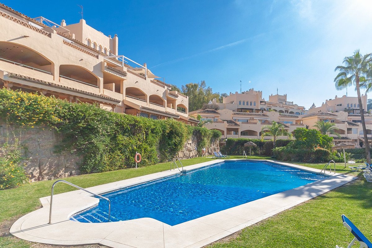 Exterior view of apartments overlooking a swimming pool and lawn on a sunny day.