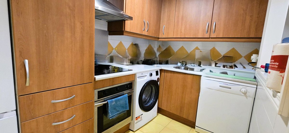 A kitchen with wooden cabinets, a washing machine, and other appliances.
