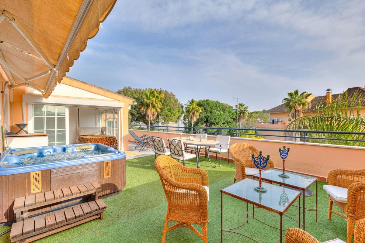 Rooftop terrace with hot tub, wicker chairs, and outdoor dining area