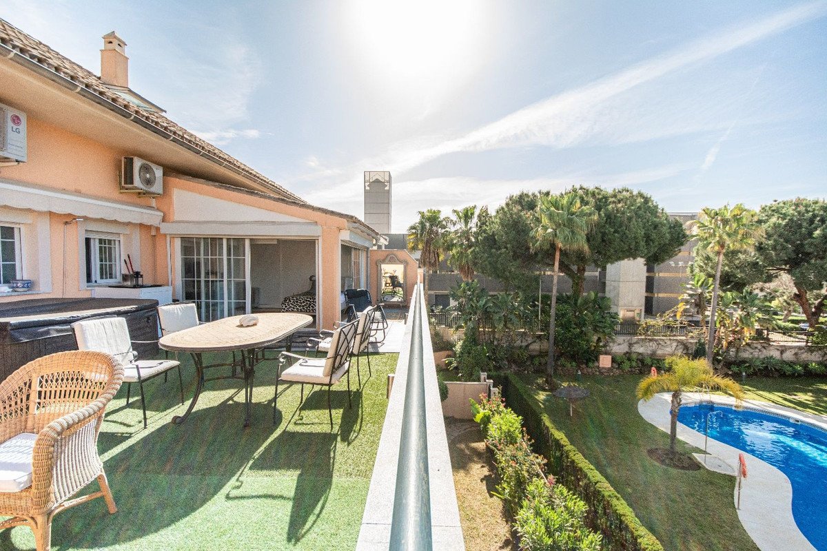 Patio with outdoor furniture overlooking a swimming pool and garden