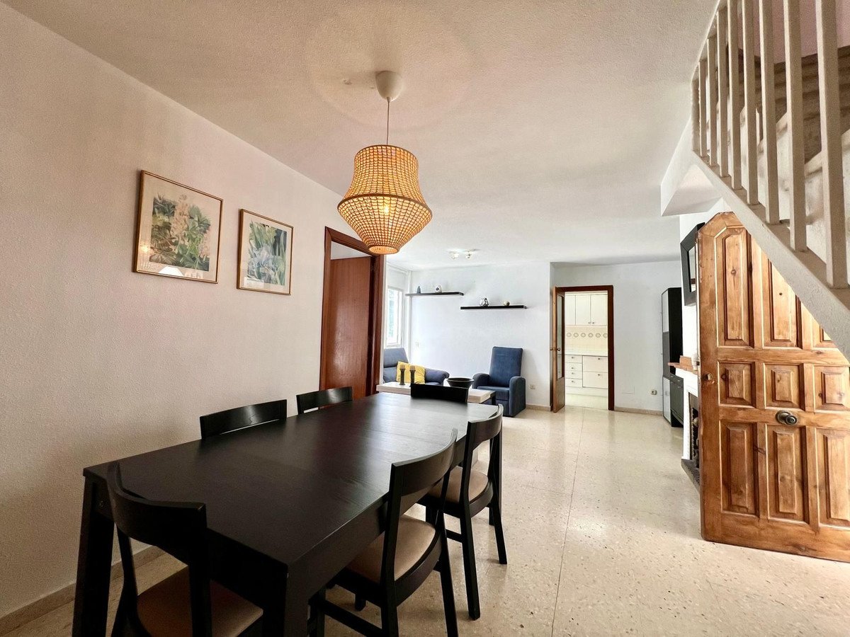 Dining room table and chairs, with view to living area, kitchen, and wooden staircase. A staircase is a wooden staircase.