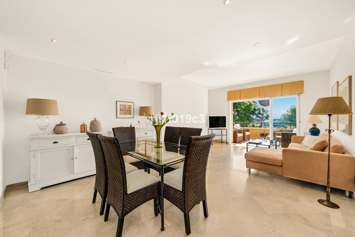 Dining and living room with sea view, glass table, and comfortable seating